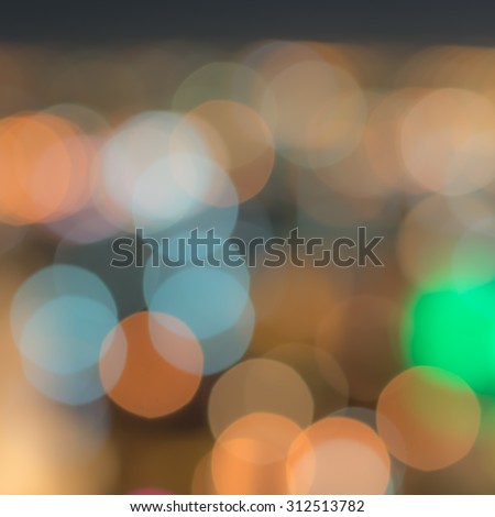 Blurred abstract background with city lights circle bokeh at night in warm vintage color tone: Colorful orange gold blue green urban nightlife illumination blurry bokeh of holiday travel vacation