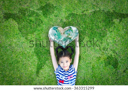 Smiling happy healthy child kid holding heart shaped green globe on world map grass background: