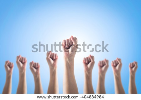 Human fist gesture among blur arm group on blue sky background: Female woman clenched hand raising up showing power strong bunch of five: Women rights strengthening empowering conceptual idea: May day