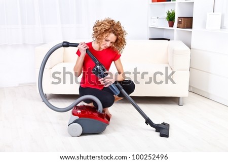 Pretty young woman repairing vacuum cleaner at home