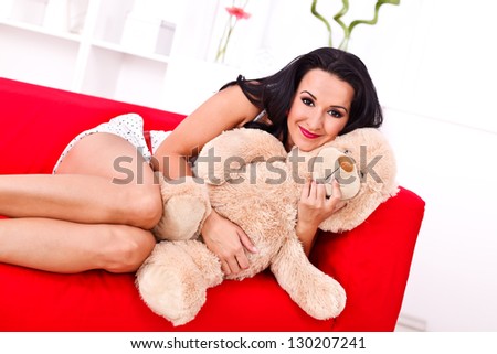Smiling girl lying on the sofa with her teddy bear
