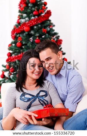 Portrait of a happy young couple sitting in front of a beautiful Christmas tree