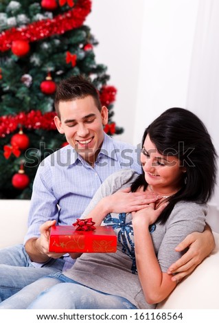 Young man giving a surprise Christmas present to his girlfriend