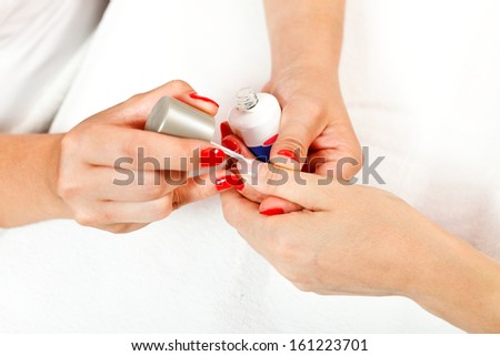 Painting a woman\'s hand with transparent nail polish.