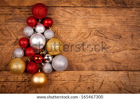 Shiny Christmas globes as a tree on wooden table, left side
