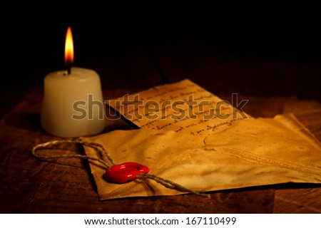 Candle near vintage envelope with red wax seal stamp