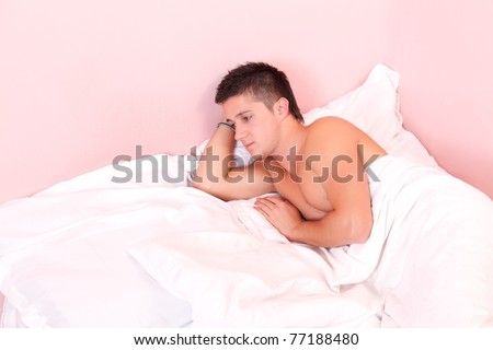 Sad man lying in double bed, looking on the empty seat