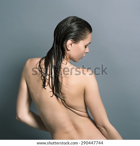 Wet naked girl standing in the studio with his back and arched her back
