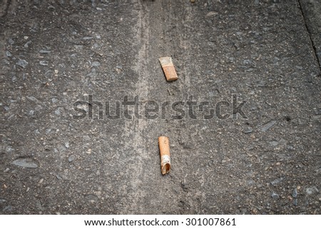 Close up cigarette butts on side street dirty floor