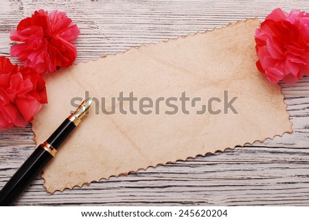 Old paper, quill pen and paper flowers on a wooden surface