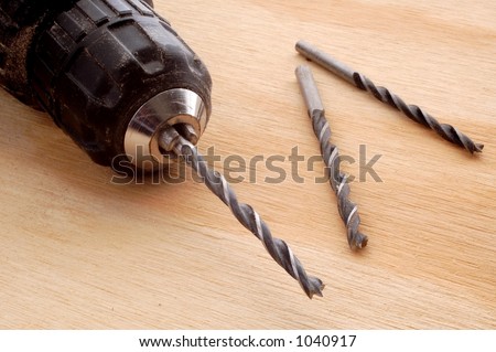 A drill chuck and drill bits on a wood board