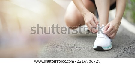 Young sporty woman preparing to run in early. Running shoes runner woman tying laces for autumn run in forest park panoramic banner. Jogging girl exercise motivation. Young woman running in the park. Foto stock © 