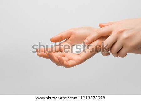 A girl smearing a handful of hand cream on her hand. Photo on gray background. Сток-фото © 