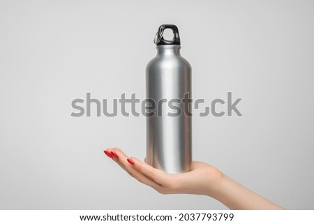 Reusable iron water bottle in a woman's hand, red nail polish Foto stock © 