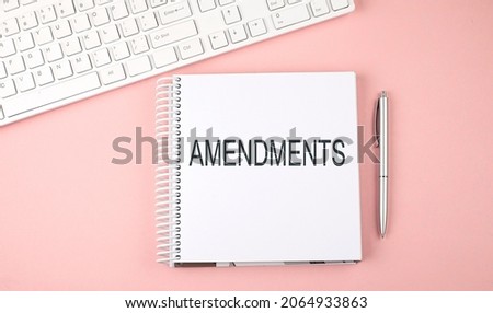 Pink office desk with keyboard and notebook with text AMENDMENTS,business Foto stock © 