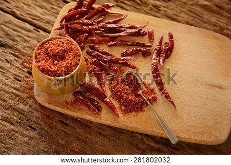 red chillies with red chilly powder on wood background