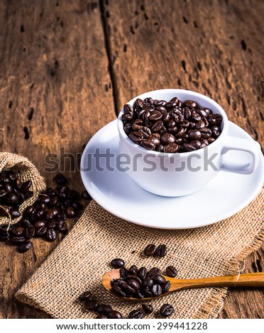 Soft focus image of coffee beans and coffee cups set on wooden background.Vintage style.(soft focus).stil life