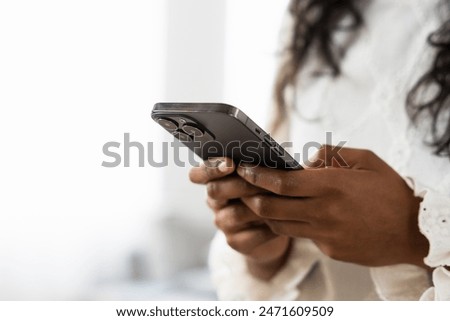 Similar – Image, Stock Photo Black woman sending a message on smartphone near sea in sunset