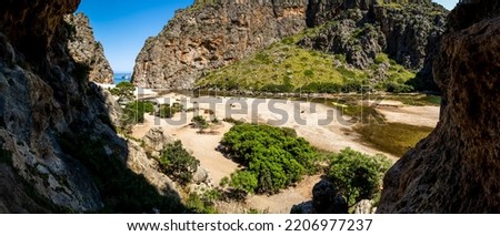 Wide panorama view from a cave to the pebble beach Cala de Sa Calobra in summer in the deepest canyon of Mallorca in the mountain range of Serra de Tramuntana with river mouth of Torrent de Pareis. Foto stock © 