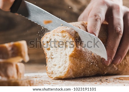 Whole grain bread put on kitchen wood plate with a chef holding gold knife for cut. Fresh bread on table close-up. Fresh bread on the kitchen table The healthy eating and traditional bakery concept Stock foto © 