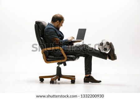 Young confident businessman sitting at desk in office. Relaxed man wearing white shirt holding cup of coffee looking away