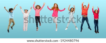Group of elementary school kids or pupils jumping in colorful casual clothes on blue studio background. Creative collage. Back to school, education, childhood concept. Cheerful girls and boys.