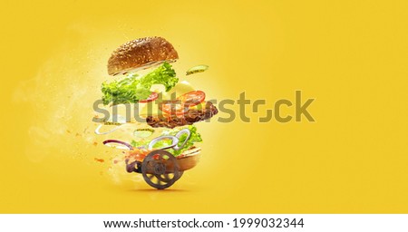 Special, express delivery. Hamburger with flying ingredients on yellow studio background. Bun, salad, meat, cheese and tomatos, onion in flight. Fast food, advertising concept. Copy space for ad.