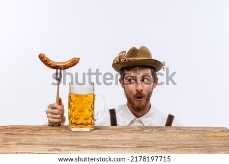 Wow. Happy man wearing traditional fest Bavarian or German outfit with big beer glass and fried sausage celebrating Oktoberfest. Alcohol, traditions, holidays, taste concept. Copy space for ad Foto stock © 