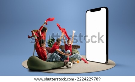 Soccer fans, win. Group of young emotional friends watching football match, sport show or movie together. Excited girls and boys sitting in front of huge 3D model of device screen at home interior Foto stock © 