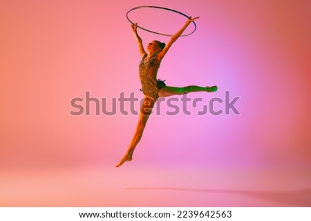 Image, Stock Photo Young slim ballerina jumping above ground in studio flexing legs.