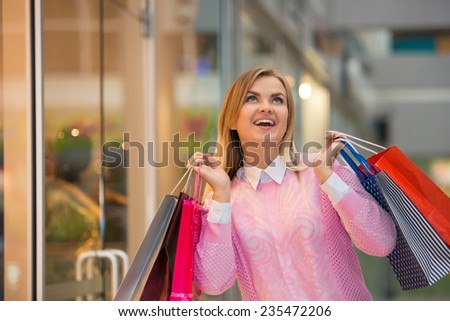 beautiful young woman goes shopping  with a fashion store window with manikin in the background.