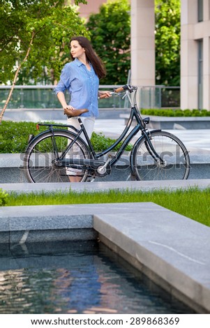 Pretty girl iin blue shirt with a bicycle at street