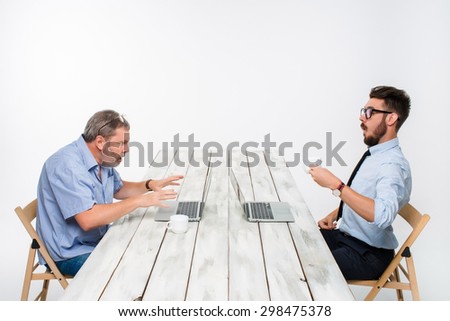 The two colleagues working together at office on white  background. both are looking at the computer screens. one man receiving good news, others are getting some bad news