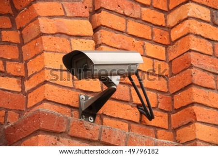 Security camera watching your every move mounted on brick wall.
