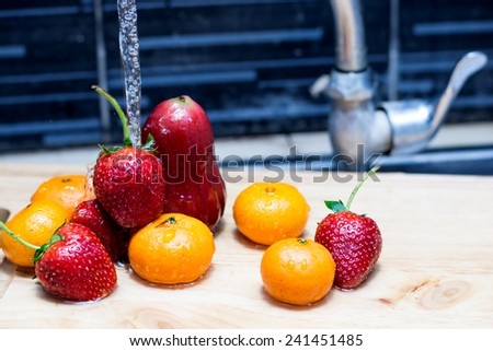 Strawberry Tangerines and Rose apple  under the pressure of water in the kitchen sink