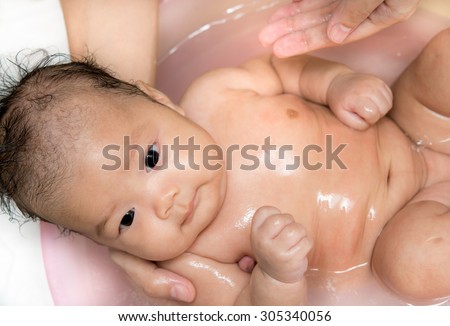 newborn baby bath in blue bathtub and mother hand, Asian Baby