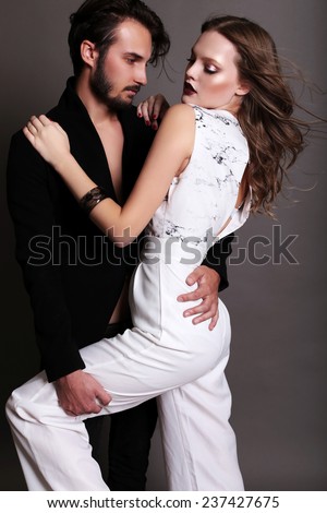 Fashion studio photo of sexy young couple of brown-haired woman and brunette man dressed in black and white suits like yin-yang and hugging and dancing on the flor,love,lovers,Valentines