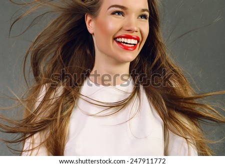 fashion portrait of blond young woman with beautiful smile,white teeth,red lips laughing and  posing at studio, the wind blowing her long hair