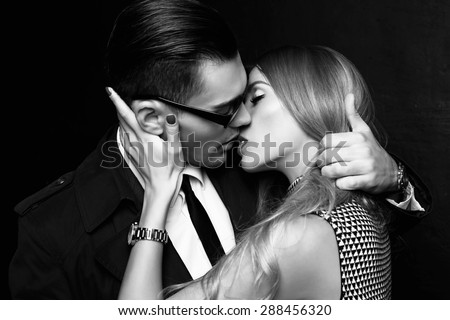 Fashion photo of office romance of sexy young lovers of beautiful blonde woman and handsome brunette businessman wearing in format suit,tie,glasses, they are hugging and kissing on Valentine\'s day