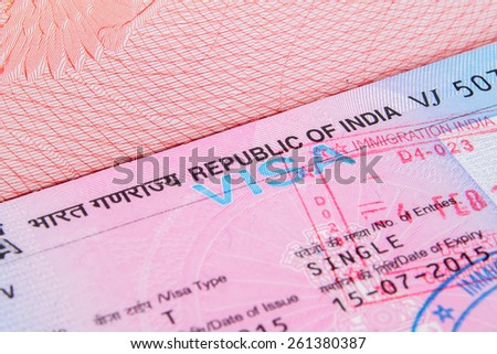 A closeup of used Indian tourist visa vignette inside a passport. Shallow DoF with focus on the word VISA single with immigration stamp  macro