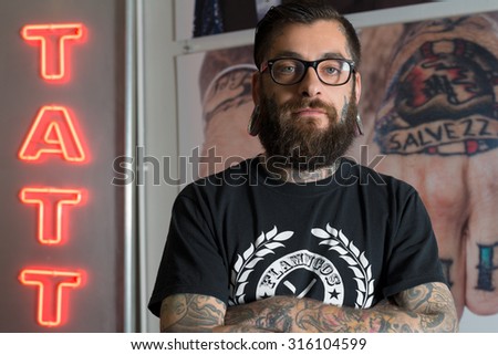 BARCELONA, SPAIN - MAY 24 2013: Portrait of happy male tattoo master. Tattoo salon mao & cathy on background