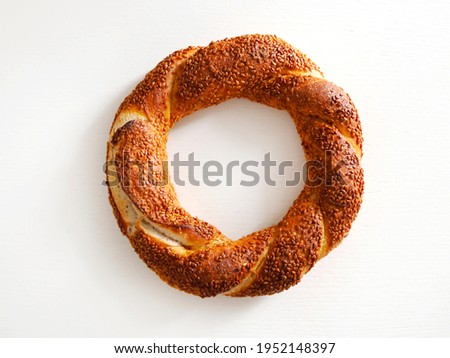 Simit or gevrek, traditional Turkish pastry food on the white wooden background. Turkish street food circular bread, bagel with sesame.