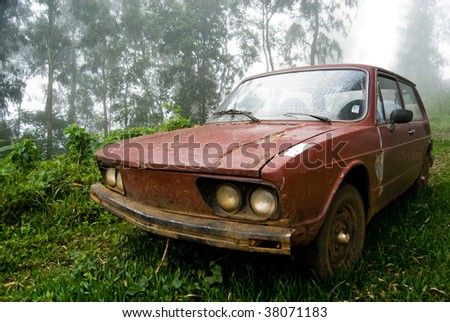 Brown old car abandoned in rural landscape with mist.