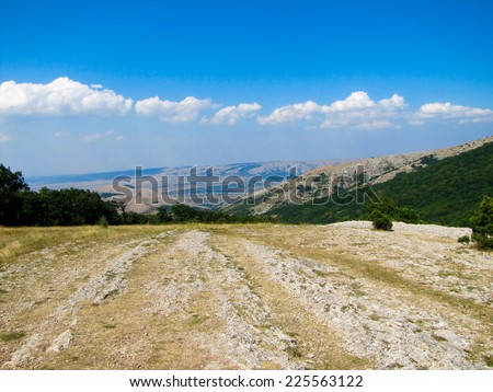 Open terrain, road and mountain landscape on sunny afternoon