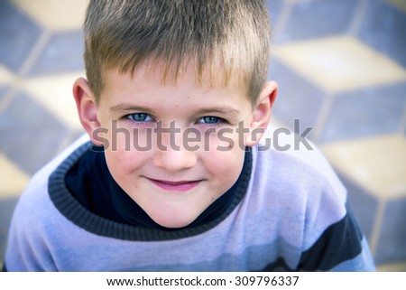 Cute little handsome boy with blue eyes smiling close-up. Adorable blonde kid, outdoor summer portrait.