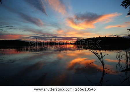 Magic sunset on the lake. Clouds reflected in the mirror clean water