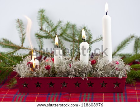 Burning candles in a advent candle wreath setting fire