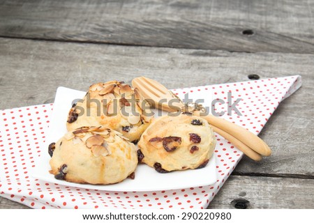 cranberry scone on the white dish, decorate with tablecloth, spoon and fork. However I attend to focus on cranberry more than decorations