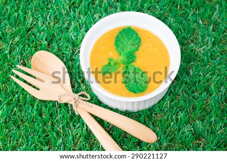 Mango panna cotta on the green background, decorate with spoon and fork. However I attend to focus on mango panna cotta more than spoon and fork