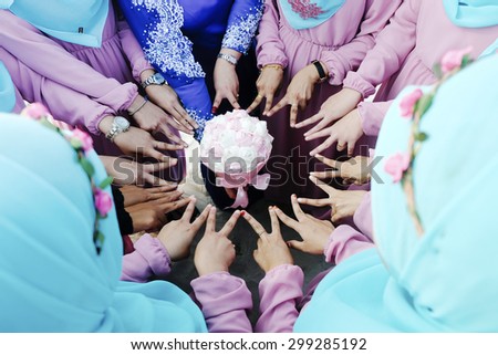 Closeup image of bride and bridesmaid point finger to wedding flower bouquet decoration to perform star symbol at outdoor location, wedding concept